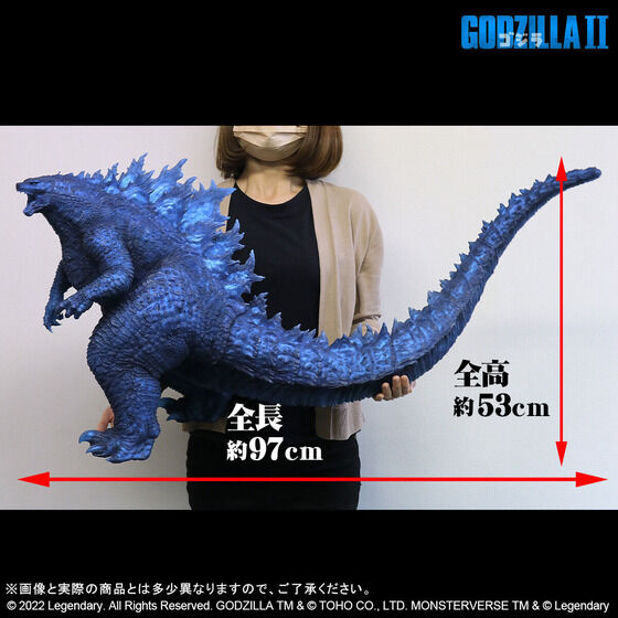 Một hình ảnh quảng cáo cho "Dòng Gigantic Godzilla (2019) Blue Clear Ver." hình ảnh từ Premium Bandai có hình chiếu bên hông của hình vì nó được giữ bởi một mô hình với các chỉ số tỷ lệ cho chiều dài 97 cm và chiều cao 53 cm.